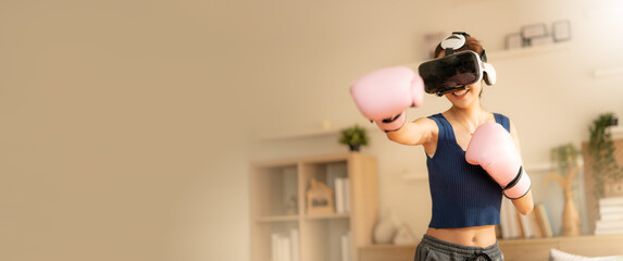 Asian female wearing VR headset for working out boxing,aerobic training for boxing punch in virtual...