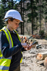 Wood quality control in the forest.  Female forester using electronic device.