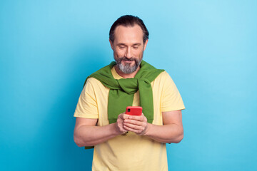 Portrait of positive man use telephone typing blog post comment isolated on blue color background