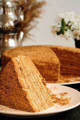 Medovik or honey cake on a white plate. Layered honey cake. Closeup view on cake slice, selective focus, vertical frame.