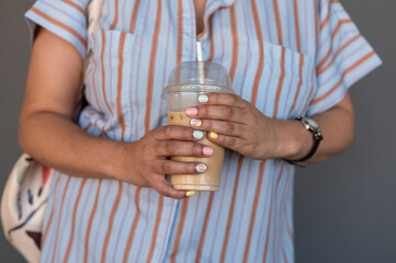 Close up shot of woman with pastel colored nails with drink