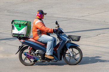  A delivery worker rides a motorcycle with a delivery box