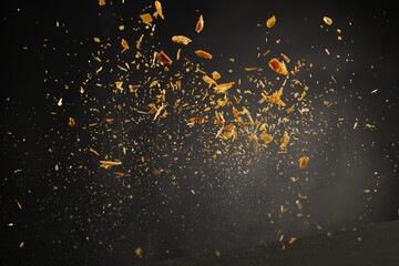 Crumb explosion, flying bread ot pastry crumbs isolated on black background