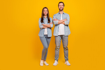 Photo of charming cheerful sister brother dressed denim shirts arms crossed smiling isolated yellow color background