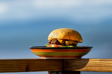Closeup of a burger on a plate on a wooden surface with a blurry background