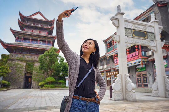Asian woman doing a selfie with smartphone in Chinese traditional town during trip