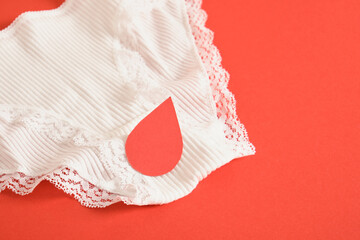 white female underwear and paper blood drop on red background
