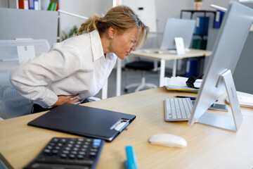 Female office worker holding her stomach because of severe pain