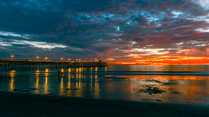 Beautiful oceanside pier at dusk with lights on over cloudy Pacific ocean