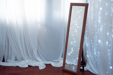 Large mirror near curtains with fairy lights