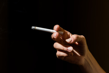  woman's hand holding cigarette, black background, addiction, vice