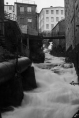 Vertical shot of the stream of the river in grayscale in Kvarndammen i Molndal