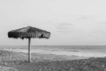 Closeup shot of a tiki hut umbrella at the San Clemente seashore in black and white