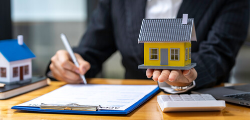 Real estate agents offer model homes with contracts for sale and purchase of houses and land. home...