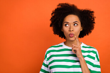 Portrait of attractive cheerful girly bewildered girl overthinking copy space isolated over bright orange color background