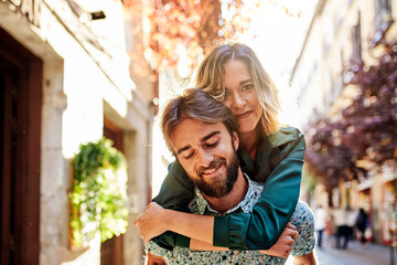 Woman piggyback on man on street.