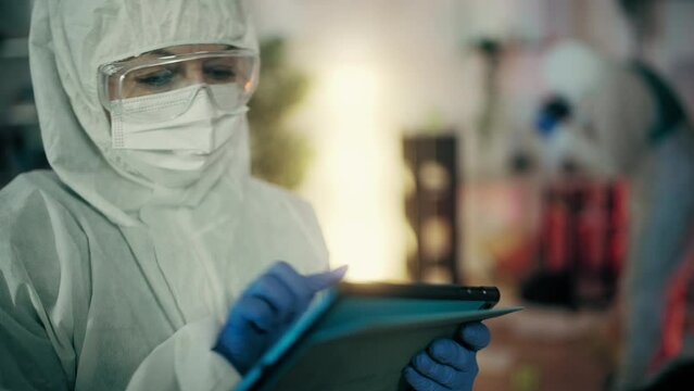 Forensic expert with tablet analyzing photos of crime scene, investigation