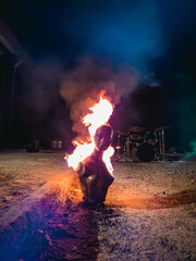 Vertical shot of a burning scary female mannequin with a drumset in the background at night