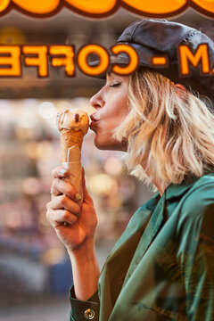 Woman licking ice cream looking through window.