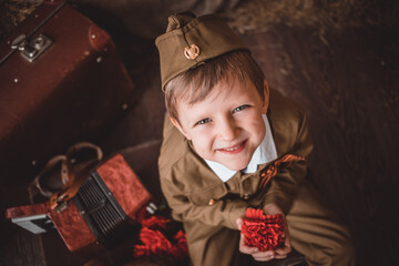 portrait of a smiling child boy in a soldier's suit with a cap in the military-patriotic zone...