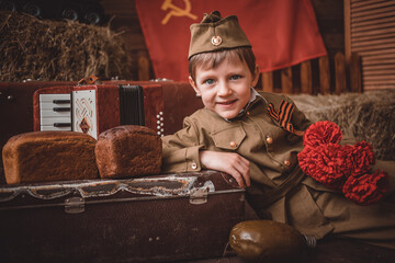 portrait of a smiling child boy in a soldier's suit with a cap in the military-patriotic zone...