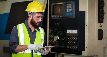 Male engineer safety helmet using a tablet to check Planning for the maintenance of metal machinery...