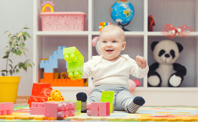 baby playing with colourful building blocks at home or kindergarten