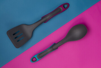 Top view of diagonally divided blue and pink sections with a kitchen scraper and a spoon on each
