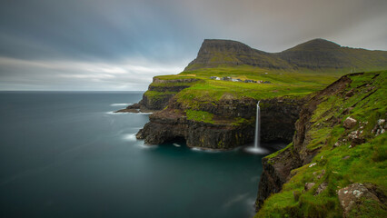 Aerial view of the Faroe Islands with a waterfall under a gloomy sky