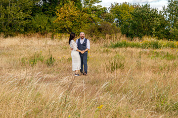 beautiful girl in a white dress and a guy in a field against a blue sky with clouds