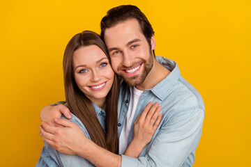 Photo of cheerful positive boyfriend girlfriend dressed denim shirts embracing smiling isolated yellow color background