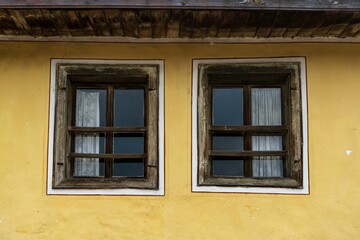 Fototapeta na wymiar Two old wooden windows on a yellow wall,old house