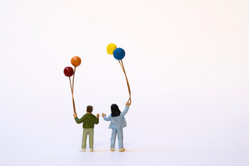 Miniature children with colorful balloons - white background, copy space