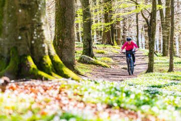 Woman cycling on trail in forest © Mikael