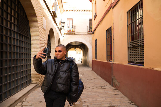 Non-binary and young person from South America is on holiday in Europe, the person is make up and wearing black clothes. He is visiting the city and takes pictures with his mobile phone. Travel