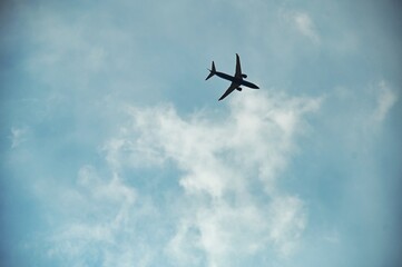 Fototapeta na wymiar view from below of airplane in flight under blue cloudy sky