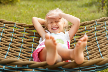 Summer holidays concept. Happy lauhging Child in Hammock have fun in Summertime in nature green...