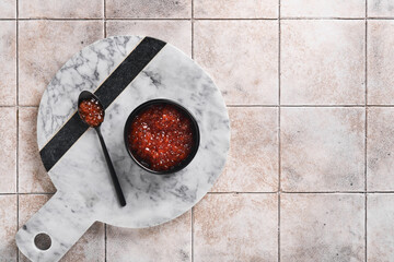 Red salmon caviar. Delicious red caviar in black bowl on old cracked tile table background. Top...