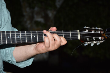 Closeup shot of a male hand holding the chords of a classical guitar