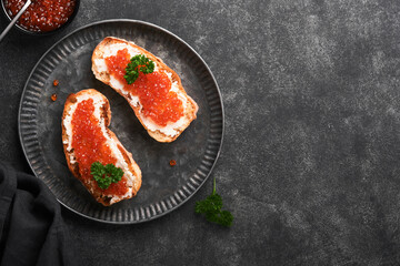 Two dandwiches with red caviar. Salmon red caviar in bowl and sandwiches server on old iron plate...