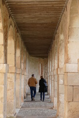 Fototapeta na wymiar Una pareja de adultos camina bajo los arcos de una iglesia.