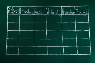 Weekly school timetable drawn on green chalkboard