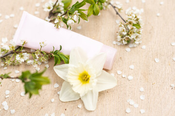 Fototapeta na wymiar Elegant cosmetic jar with cherry blossoms on white background. Side view