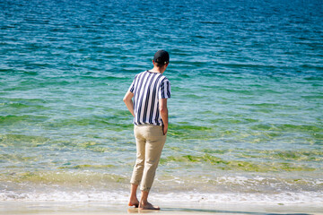 relaxed man walking along the shore of the beach