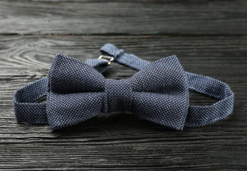 Stylish blue bow tie on black wooden background, closeup