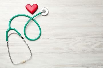 Stethoscope and red heart on white wooden table, flat lay with space for text. Cardiology concept