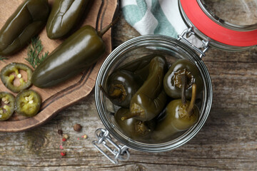 Pickled green jalapeno peppers on wooden table, flat lay