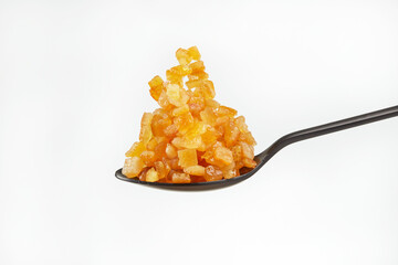 Black spoon with a pile of candied fruits on a white background. Shallow depth of field	