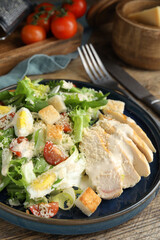 Delicious Caesar salad in bowl on wooden table, closeup