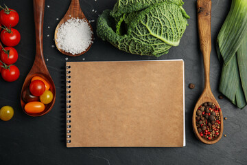 Recipe book and different ingredients on black table, flat lay with space for text. Cooking classes